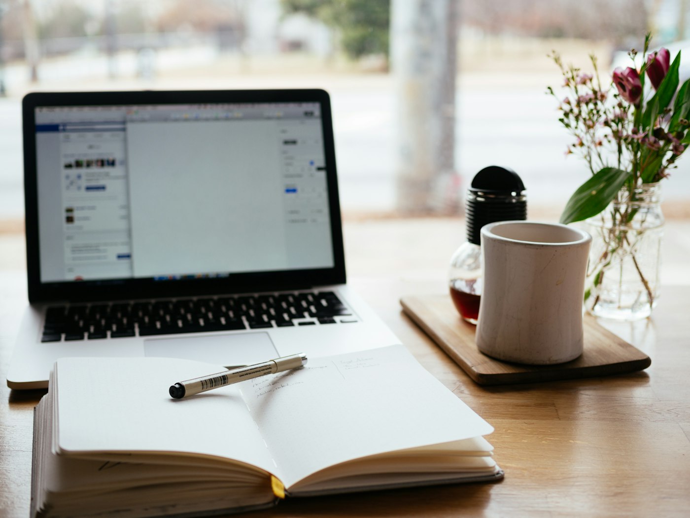 An open notebook and laptop on a bright desk.