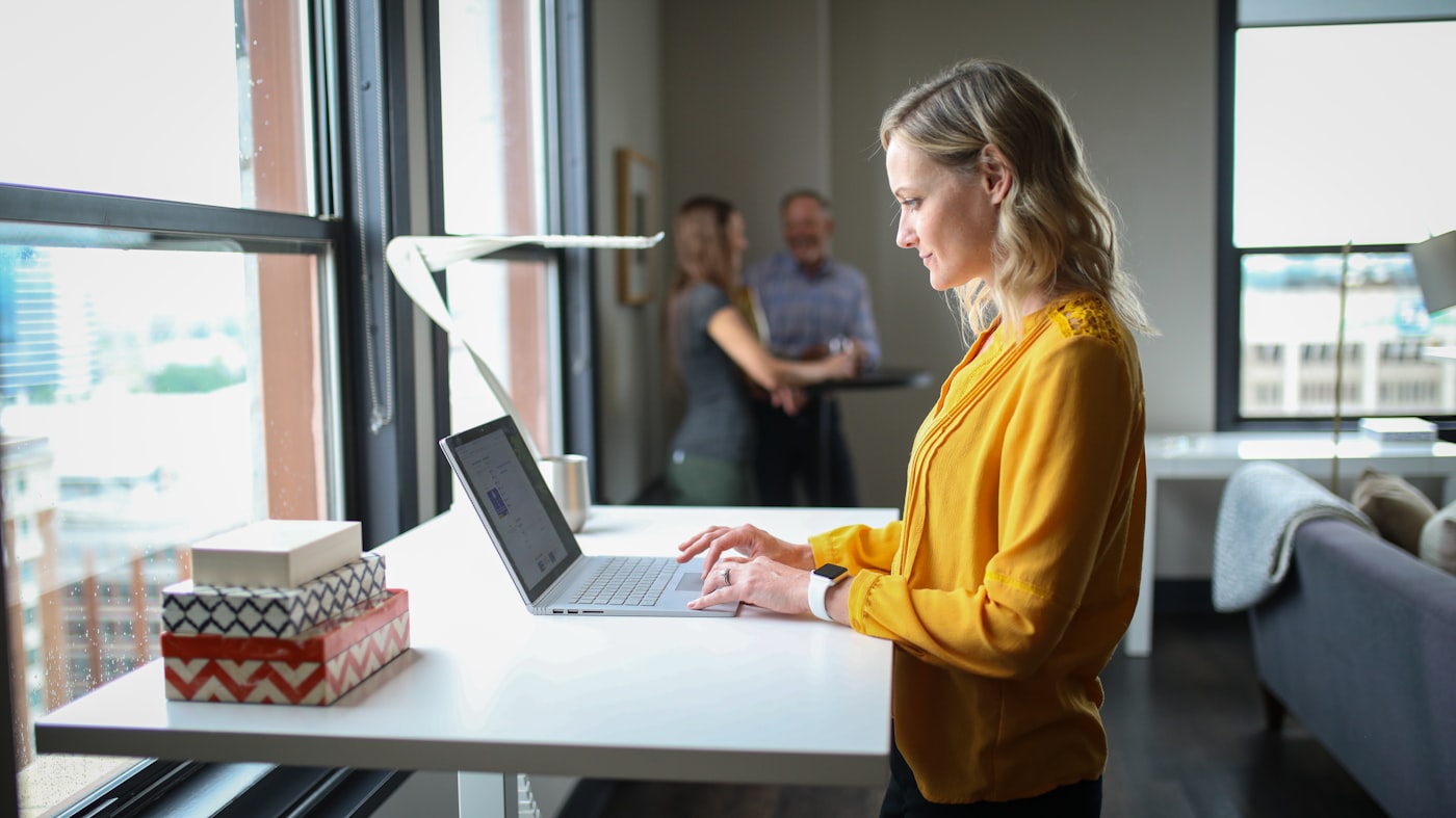 A practitioner working on a laptop in a bright office.